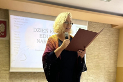 Kobieta stoi z mikrofonem i teczką w ręcach