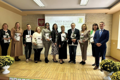 Grupa osób, z kwiatami w rękach stoi i pozuje do zdjęcia