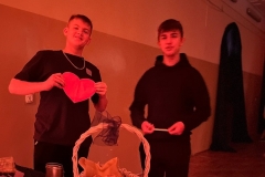 Uczniowie stoją, jeden trzyma w rękach serce przednimi na stoliku stoli koszyk