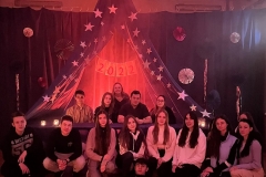 Uczniowie pozują do zdjęcia, w tle dekoracja z granatowego materiału i gwiazd