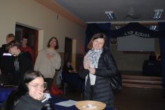 Nauczycielka i uczniowie stoją, w tle napis andrzejki