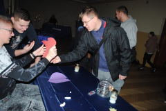 Uczeń trzyma w rękach serce z papieru, obok stoją inni uczniowie, na stoliku stoją świeczki, leży papierowe serce