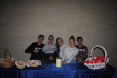 Młodzież siedzi przy stole na którym stoją koszyki z ciastkami