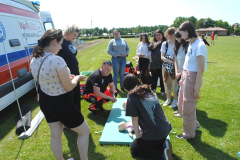 Jedna osoba klęczy przy fantomie, pozostałe stoją, w tle niebo