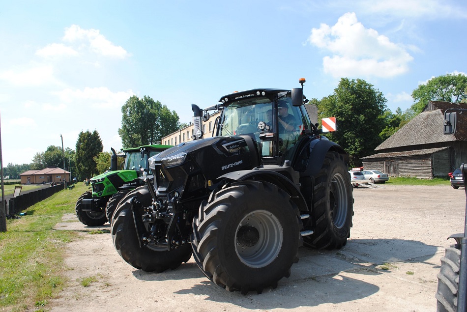 Zaparkowane ciągniki stoją, w tle drzewa, budynki