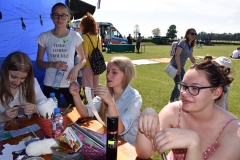 Uczestnicy pikniku siedzą i plotą makramę