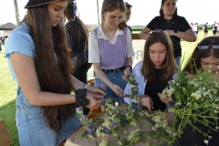 Uczestnicy pikniku wiją wianki z roślin