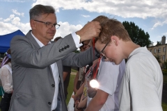 Wicestarosta Powiatu Piotrkowskiego zawiesza na szyi uczestnika Międzyszkolnego Turnieju w Piłce Nożnej medal