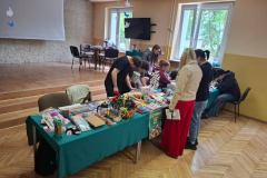 Grupa osób stoi przy stole na którym leżą fanty