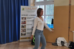 Kobieta tańczy, w tle baner reklamujący szkołę