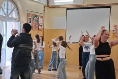 Grupa osób tańczy, w tle rzutnik ekranu