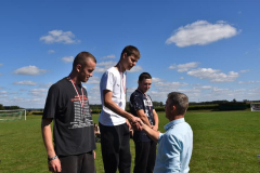 Dyrektor gratuluje uczniom stojącym na podium