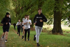 Uczniowie biegną w tle drzewa