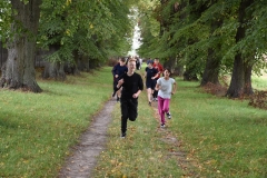 Uczniowie biegną ścieżka wśród drzew