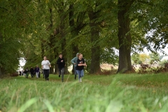 Uczniowie biegną w tle drzewa