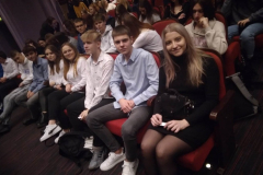 Uczniowie siedzą, w tle inne osoby