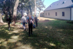 Młodzież z workami w rękach idzie przez park, w tle budynek