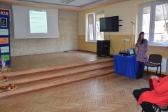 Kobieta stoi, w tle telewizor, okna