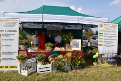 Zdjęcie przedstawia nauczycieli stojących pod namiotem, przed nimi na stoliku stoją kwiaty