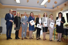 Nauczyciele stoją na scenie z dyplomami w rękach