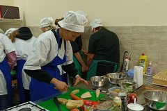 Uczniowie kroją warzywa na desce