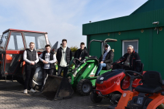 uczniowie pozują do zdjęcia przy ciągniku i kosiarkach samojezdnych