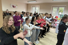 Uczniowie tańczą, w tle okna