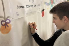 Uczeń maluje na ścianie z papieru, w tle napis Ściana pozytywnych myśli