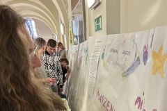 Uczeń maluje na ścianie z papieru, w tle inne osoby