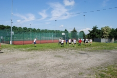 Uczniowie biegną, w tle płot, drzewa