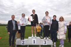 Uczennice stoją na podium, obok stoją nauczyciele