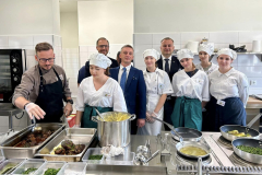 Uczniowie stoją przy kuchni z garnkami