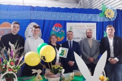 Uczniowie z nauczycielka stoją, przed nimi żółte i zielone balony