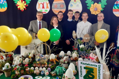 Wicestarosta Powiatu Piotrkowskiego, nauczycielka i uczniowie pozują do zdjęcia w tle kolorowe pisanki i balony