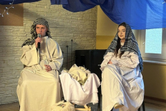 Maryja i Józef siedzą w żłóbku leży Jezus