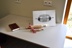 Książka, wałki do ciasta oraz logo szkoły leżą na stole