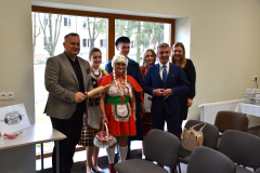 Mężczyzna z wałkiem w ręku, czerony kapturek oraz inne osoby pozują do zdjęcia