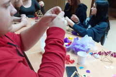 Uczniowie siedzą przy stole na którym leżą kawałki bibuł w różnych kolorach