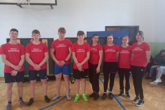 Uczniowie w czerwonych koszulkach pozują na stojąco do zdjęcia