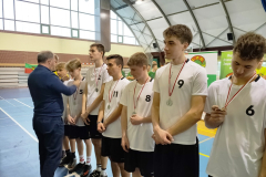 Mężczyzna zawiesza medale uczniom