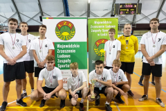 Uczniowie z medalami na szyi i pucharem pozują do zdjęcia, w tle napis Wojewódzkie Zrzeszenie Ludowe Zespoły Sportowe