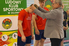 Mężczyzna wręcza uczniowi medal