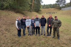 Uczniowie stoją, w tle drzewa, łąka