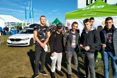 Uczniowie stoją, w tle namioty, samochód