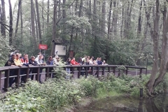 Uczniowie stoją oparci o barierkę nad wodą, w tle drzewa