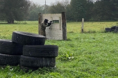 Uczeń stoi przy ścianie, w tle opony, drzewa