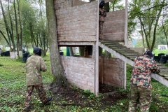 dwóch uczniów stoi przy drewnianym schronie