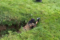 Uczeń leży w okopie, w tle trawa