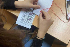 w rękach trzymany jest biały materiał oraz igła z nitką