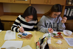 Dziewczęta lukrują pierniki leżące na talerzach